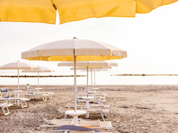 Beach with yellow umbrellas at sunset.