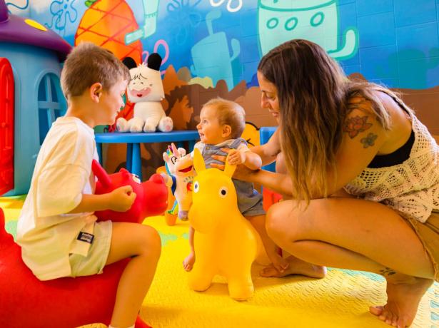 Children happily play on inflatable animals in a colorful room.